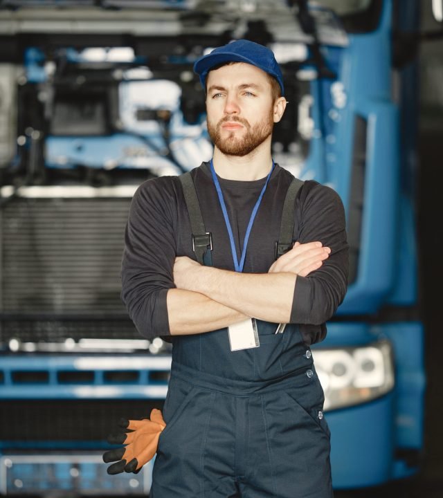 Worker in uniform. Man repairs a truck. Man with tools